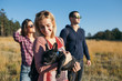 Small group of teenagers enjoying outdoors with beautiful black French bulldog. Sunny day. Autumn mountain nature. 