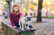 Beautiful redhead girl enjoying autumn day in a park with her French bulldog puppy. 