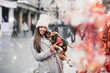 Beautiful brunette woman standing with her adorable French bulldog next to candies selling on street.